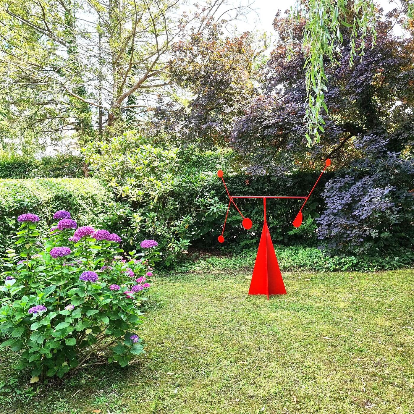 Petite lune rouge sur une pelouse entourée d'hortensias